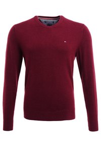 Vinröd stickad tröja med långa ärmar, rund halsringning och ribbade muddkanter. Har en liten logotyp på bröstet. Mjuk textur.