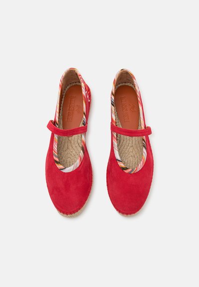 Sapatos de camurça vermelhos com bico redondo, apresentando um acabamento em tecido estampado colorido e uma tira atravessando o peito do pé. Sola de juta texturizada.