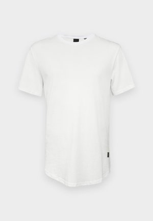 T-shirt branca de manga curta, feita de algodão, apresentando um decote redondo e uma parte traseira ligeiramente alongada, com um pequeno logótipo em destaque na lateral.