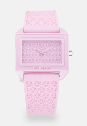 Pink Guess wristwatch with rectangular face, patterned dial and strap, silver crown, and two pink hands showing time.