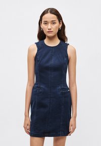 Námornícka rifľová šaty bez rukávov, s okrúhlym výstrihom, viditeľným prešitím a dvoma prednými vreckami. Vyznačuje sa priliehavým strihom a textúrovanou tkaninou.