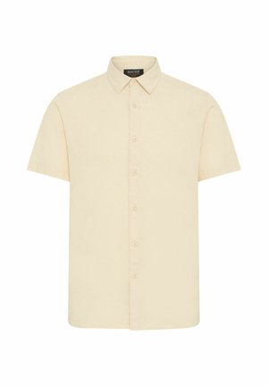 Camisa de manga corta en tejido beige claro, con un cierre frontal de botones, cuello puntiagudo y una textura suave. Sin patrones ni acentos visibles.