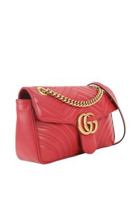 Sac à main matelassé en cuir rouge avec bandoulière chaîne dorée et emblème double G en or sur le rabat avant.