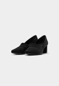 Black high-heeled shoes with a pointed toe, made of soft fabric. Features crisscross straps and a sturdy block heel. Simple design.