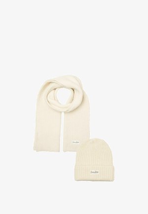 Gebreide crèmekleurige sjaal en muts set. De sjaal heeft een geribbelde textuur; de muts heeft een omgeslagen manchet en een subtiele logo-tag.