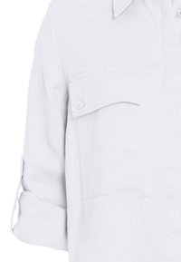 Weißes Leinenhemd mit Button-Down-Kragen, zwei Brusttaschen und hochgekrempelten Ärmeln, mit strukturiertem Stoff.