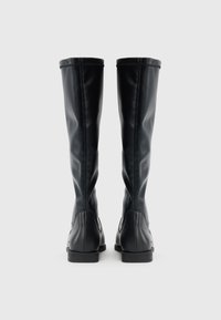 Μαύρες μποτάκια μέχρι το γόνατο από λείο συνθετικό υλικό με εφαρμοστή σχεδίαση, στρογγυλεμένη μύτη και χαμηλό επίπεδο τακούνι. Ορατά ράμματα για διακοσμητικό αποτέλεσμα.