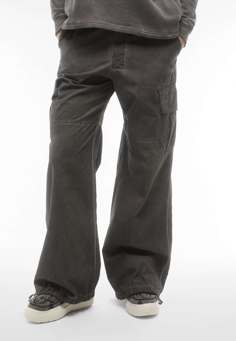 Pantaloni cargo grigi scuri con una vestibilità rilassata, dotati di tasche laterali e polsini elasticizzati. Il materiale sembra avere una consistenza testurizzata con una finitura opaca.