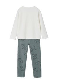 White long-sleeve top paired with grey pants featuring a printed pattern of cartoon lions. Soft fabric with a smooth texture.