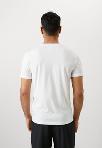 White cotton t-shirt with a crew neckline, short sleeves, and a plain design; displayed from the back, showing a smooth texture.
