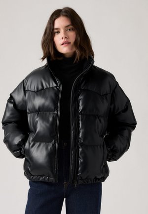 Casaco puffer preto em material brilhante, com colarinho alto, fecho de zíper e punhos elásticos. Forma ampla com secções acolchoadas.