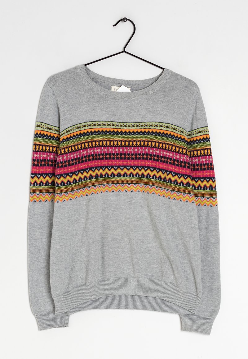 Pull en gris clair avec des motifs géométriques horizontaux colorés en rose, orange, vert et noir sur la poitrine et les manches, suspendu à un cintre noir.