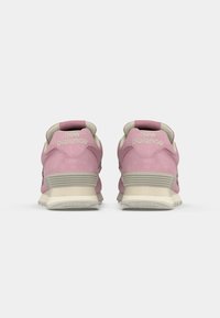 Pantofi sport din suede roz, cu talpă din cauciuc bej, având accente gri deschis și logo-ul "New Balance" pe călcâi și pe lateral.
