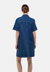 Robe chemise en jean bleu foncé, manches courtes, col, style boutonné, avec des coutures blanches et une coupe décontractée jusqu'aux genoux.