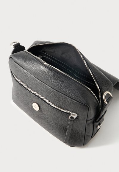 Μαύρη υφασμάτινη δερμάτινη τσάντα crossbody με μπροστινή τσέπη με φερμουάρ και ανοιχτό κύριο διαμέρισμα, που δείχνει μαύρη υφασμάτινη επένδυση και εσωτερική τσέπη με φερμουάρ.