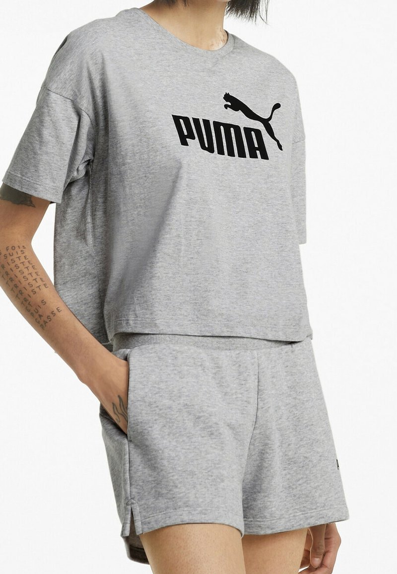 Harmaa puuvillainen lyhythihainen t-paita, jossa on musta "PUMA" -logo, paritettu harmaiden shortsien kanssa, joissa on sivutaskut ja rento istuvuus.
