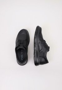 Zapatos de cuero negro con un acabado texturizado, puntera redonda, diseño con cordones y suelas de goma. Uno de los zapatos está ligeramente inclinado para mayor visibilidad.