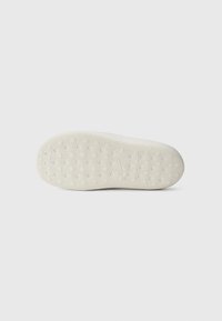 White rubber shoe sole with textured pattern and circular grip points, featuring a smooth, flat edge and a slightly raised heel.