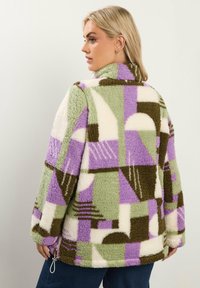 Fleece jack met een geometrisch patchwork in lavendel, groen, bruin en crème. Hoge kraag en trekkoord aan de onderkant. Zachte textuur.