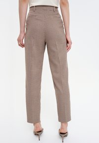 Pantalone u uzorku hounds-tooth u smešnim i krem bojama, s visokim strukom i ravnim nogavicama. Tkanina izgleda teksturirano; sadrži bočne džepove i petlje za remen.