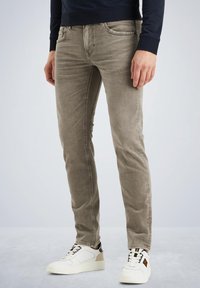 Jeans de mezclilla gris con un diseño ajustado y ligero estiramiento, que cuentan con cinco bolsillos y costuras en contraste, combinados con zapatillas blancas.