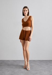 Bronse strikket crop topp med bred utringning, kombinert med matchende høyt liv shorts med belteknute, komplementert med snøresandaler.