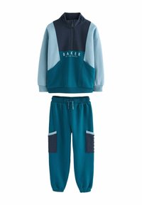 Sudadera bloqueada en colores azul verdoso y marino con cuello alto y bolsillo frontal, combinada con joggers a juego que cuentan con bolsillos laterales y puños acanalados.