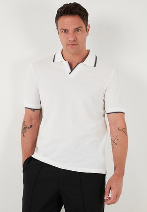 Hvid polo t-shirt med struktur, korte ærmer og v-halsudskæring. Har sort-hvide stribede detaljer på kraven.