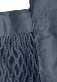 Zila soma ar jauktu gludu audumu un teksturētu nešanu. Iezīmējas ar izšūtām akcentu detaļām un taisnstūra rokturi. Vispārējā krāsa ir maiga zila.