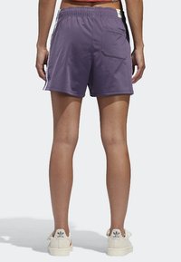 Purple athletic shorts with an elastic waistband, featuring a back pocket, smooth texture, and short inseam for mobility.
