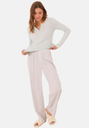 Light blue ribbed long-sleeve top with a henley neck; white pants with red vertical stripes; paired with cream-colored slippers.