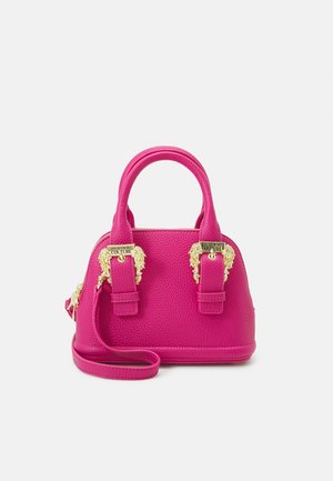 Pink tekstureret håndtaske med guld løvehoved-detaljer, dobbelte håndtag og aftagelig skulderrem. Kompakt, struktureret design.