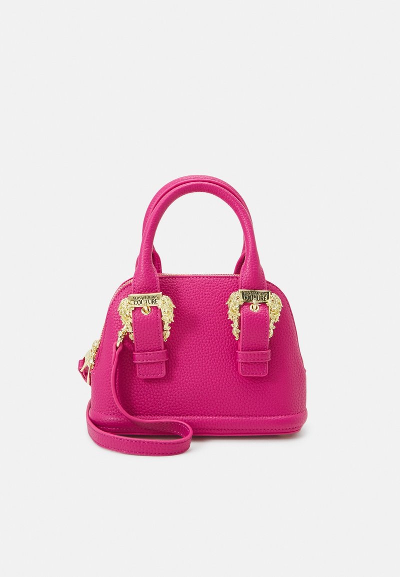 Růžová texturovaná kabelka se zlatými lvími hlavami jako ozdobami, dvojitými držadly a odnímatelným ramenním popruhem. Kompaktní, strukturovaný design.