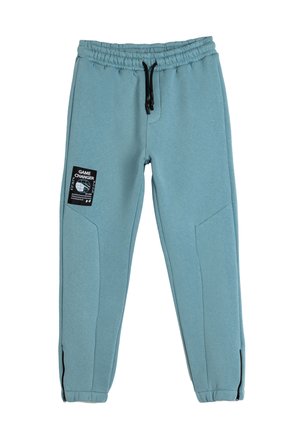 Hellblaue Jogginghose aus weichem Material, mit Kordelzugbund, Seitentaschen und einem schwarzen „GAME CHANGER“-Label am Bein.