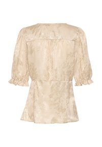 Top color beige chiaro con una finitura leggermente lucida, maniche a sbuffo, polsini arricciati e orlo svasato. Texture liscia con un motivo sottile su tutta la superficie.