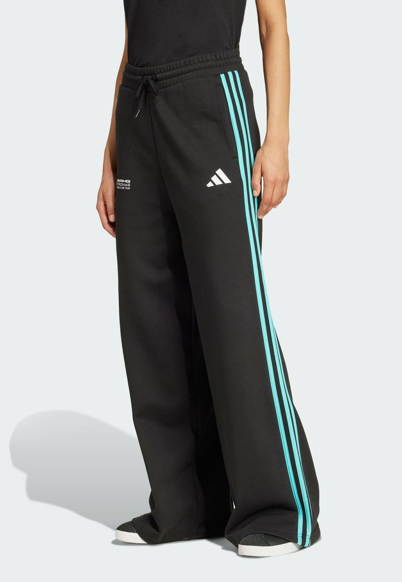 Crne trenirke s opuštenim krojem, s tirkiznim bočnim prugama i bijelim Adidas logom. Izrađene su od mekog, udobnog materijala.