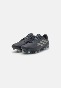 Scarpe da calcio nere con design aerodinamico, upper in pelle texturizzata e accenti argentati riflettenti. Presentano tacchetti sagomati per la trazione.