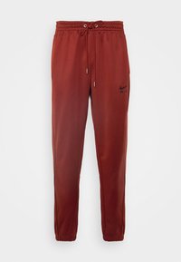 Maroon joggers made of soft fabric with an elastic waistband, adjustable drawstring, and a black logo printed on the left leg.