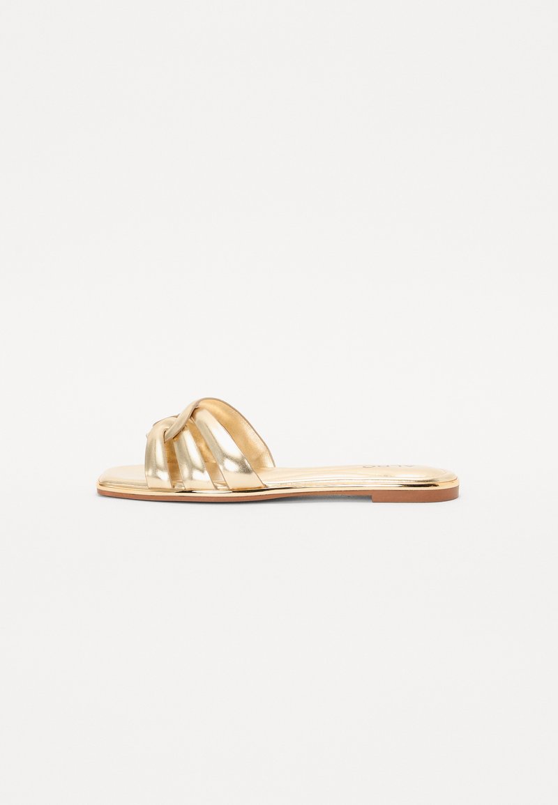 Metallisk gull sandal med knyttet stroppdesign, flat såle og glatt tekstur. Passer til hverdagsbruk i varmt vær.