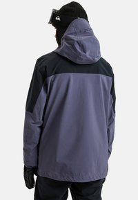 Paarse en zwarte skijas met een capuchon, beschikt over textuurstof, een ontspannen pasvorm en verstelbare mouwopeningen.