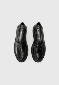 Black leather loafers with a rounded toe, featuring a strap across the front, stitched detailing, and a textured rubber sole.