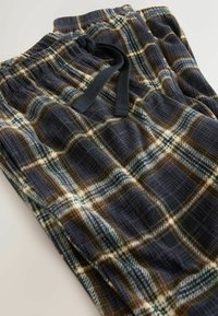 Flanellpyjamahosen mit einem dunklen Marineblau, Beige und weißen Karomuster. Sie verfügen über einen elastischen Bund mit einem Zugband zur Anpassung.