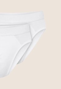 Białe bawełniane slipy o gładkiej fakturze, z logo wytłoczonym na koronkach i klasycznym kroju. Wyeksponowane dwie pary.