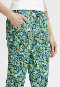Blommiga byxor med en grön bakgrund och blåa och gula blommor, dragsko i midjan och sidofickor. Lättviktsmaterial.