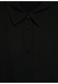 Chemise noire à col avec devant à boutons comportant cinq boutons noirs ronds espacés uniformément.