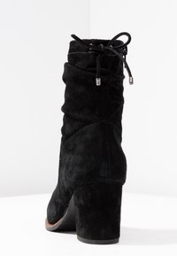Stivale alla caviglia in suede nero con design arricciato, punta arrotondata e tacco a blocco di altezza media. Presenta lacci e occhielli metallici nella parte superiore.