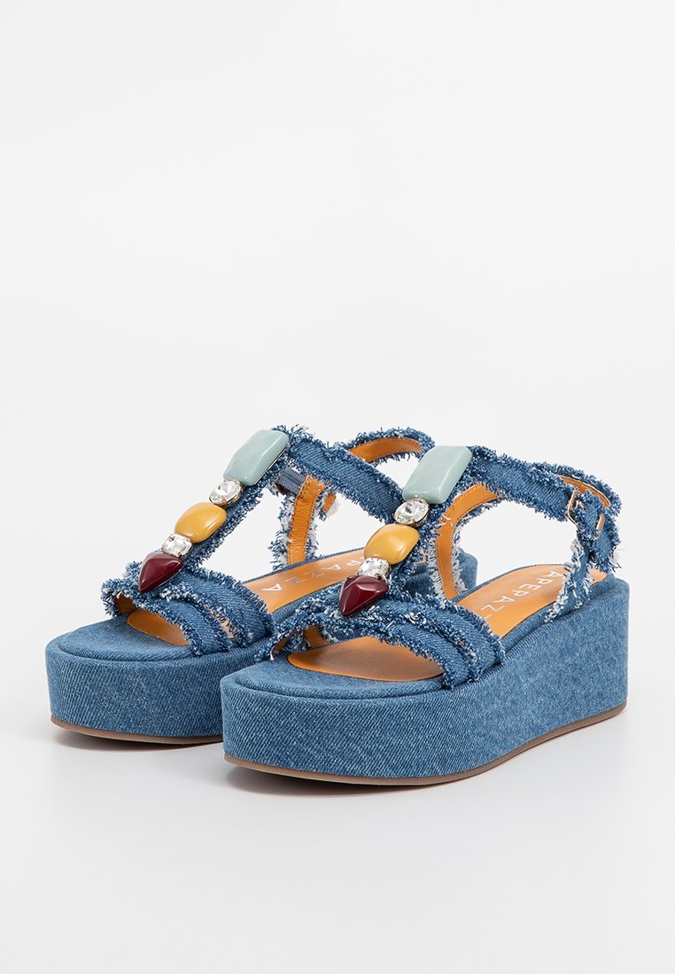 Sandali con plateau in denim con bordi sfrangiati, dotati di perline decorative multicolori e una tomaia in tessuto blu testurizzato. Suola in gomma marrone.