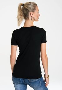 Black short-sleeve t-shirt with a crew neck. Made of smooth fabric, fitted shape, with rolled sleeves and a clean hem.