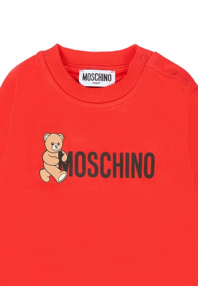 Camicia rossa in cotone a maniche lunghe con logo nero "MOSCHINO" e grafica di un orsetto cartone. Collo rotondo a coste e bottoni a pressione.