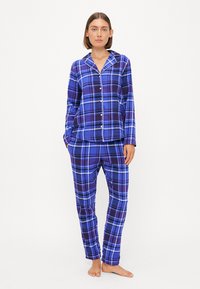 Ensemble de pyjama à carreaux dans des tons variés de bleu et de violet, comprenant un haut à boutons et un pantalon à taille élastique, fabriqué à partir d'un tissu doux.